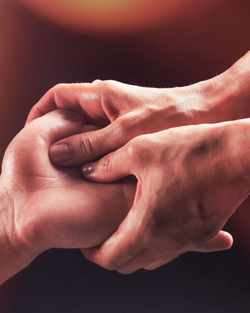 girl masseur doing hand massage to man on dark background close-up, beautiful relaxation massage, recovery